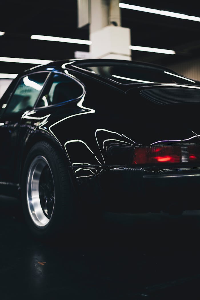 Elegant classic black car with shiny chrome and rear lamp visible in an indoor setting.